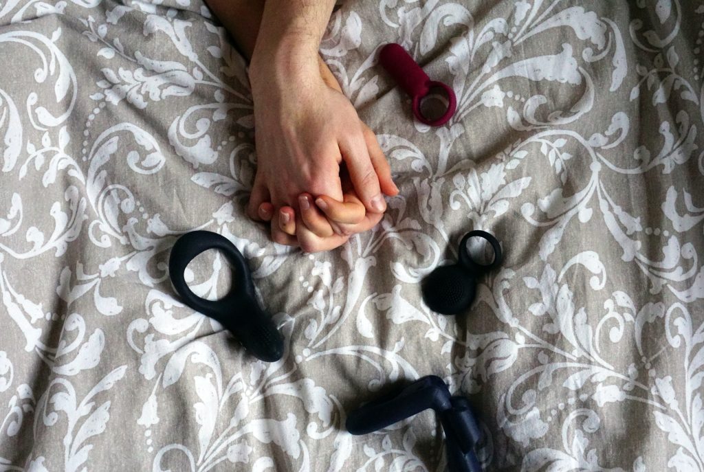couple holding hands with cock rings on the bed